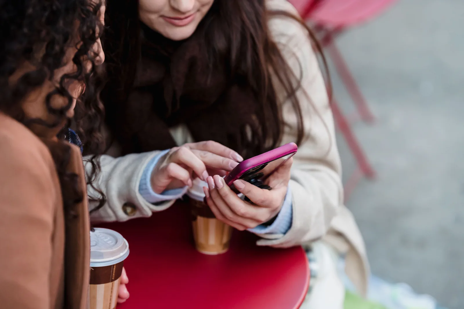 Two friends looking at a phone together over coffee in a cafe