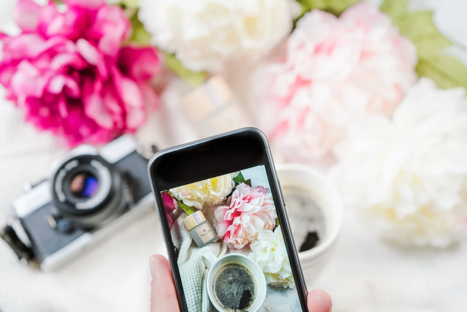 Phone taking a photo of a flower arrangement on a table